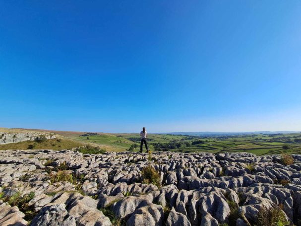 Walker looking over landscape view, standing of sandstone