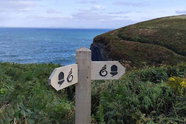 National Trail wooden sign post with coast path in background