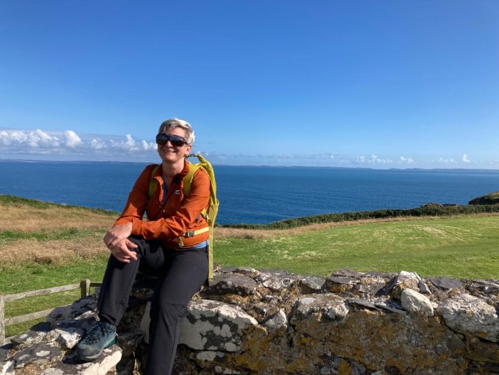 Alex sitting on rocks on coast path