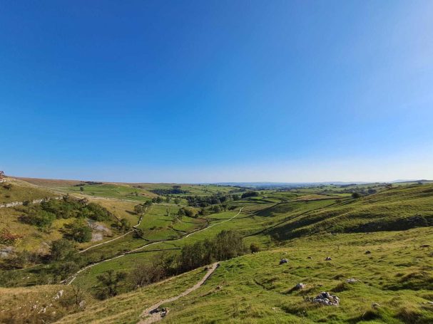 Pennine way path leading up hill over green landscape